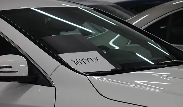 Valkoinen auto jonka tuulilasissa on myyty-kyltti